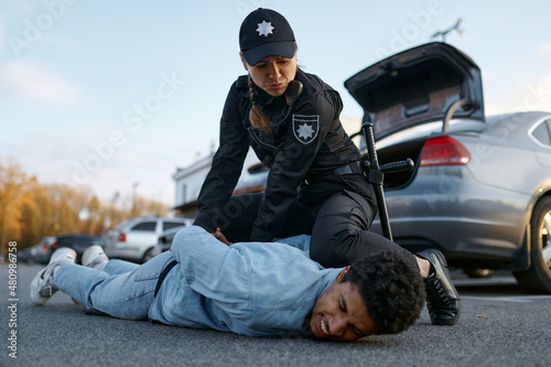 Fototapeta Police officer arresting suspicious young car driver