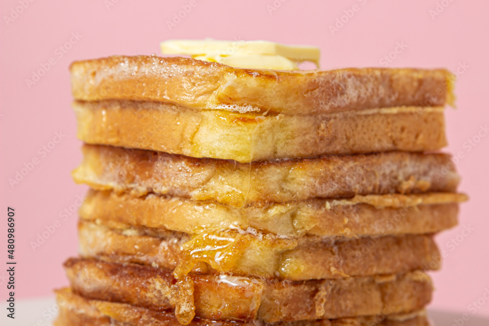 eggy bread on a pink background. Butter melts on a stack of eggy breads. Tasty breakfast. eggy bread on a pink background. Butter melts on a stack of eggy breads. Tasty breakfast.