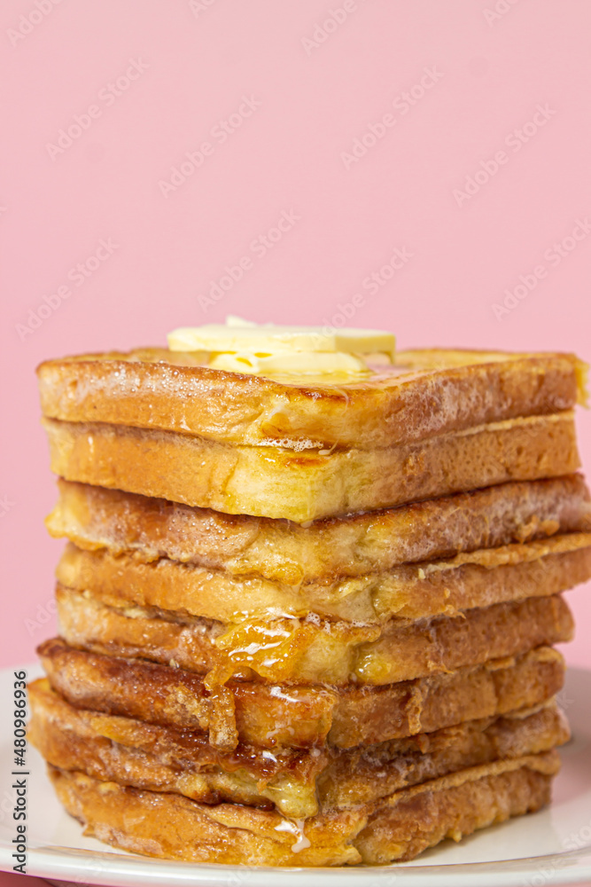 eggy bread on a pink background. Butter melts on a stack of eggy breads. Tasty breakfast.