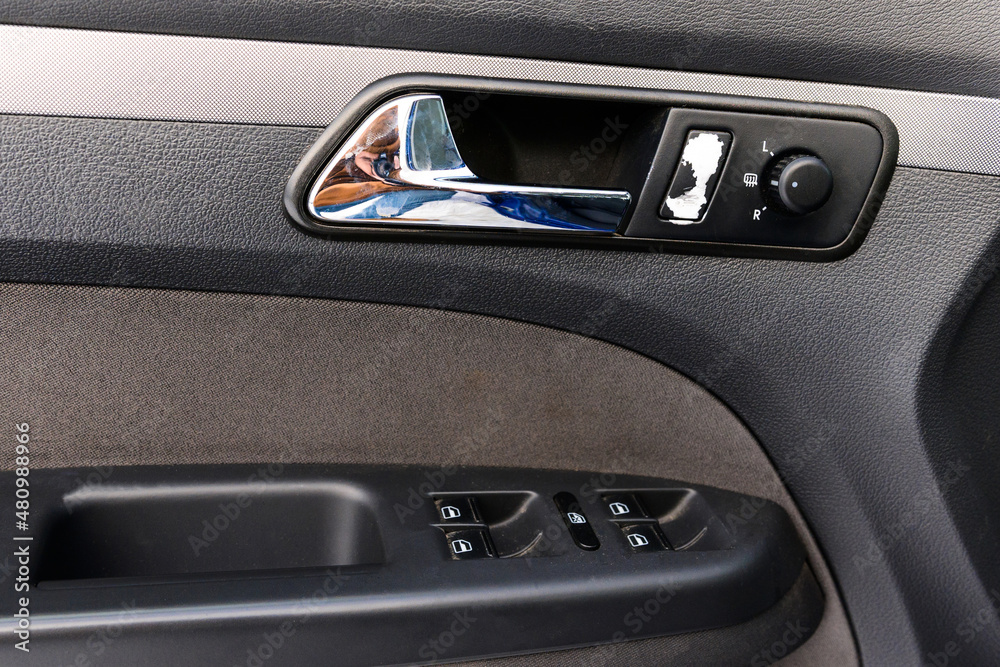 Inside the drivers door of a car with a window lifter. Car door handle. Automatic adjustment of mirrors.