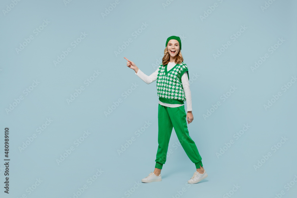 Full size vivid young brunette girl teen student wears checkered green vest hat go move point aside on workspace area copy space mock up isolated on plain pastel light blue background studio portrait. Full size vivid young brunette girl teen student wears checkered green vest hat go move point aside on workspace area copy space mock up isolated on plain pastel light blue background studio portrait.