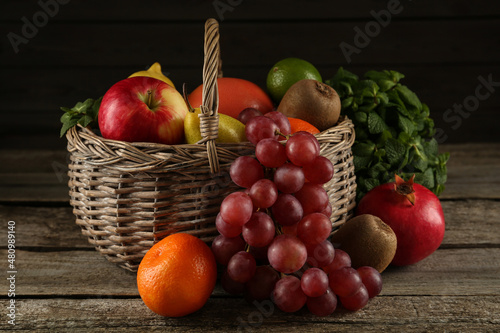 Fresh ripe fruits and wicker basket on wooden table