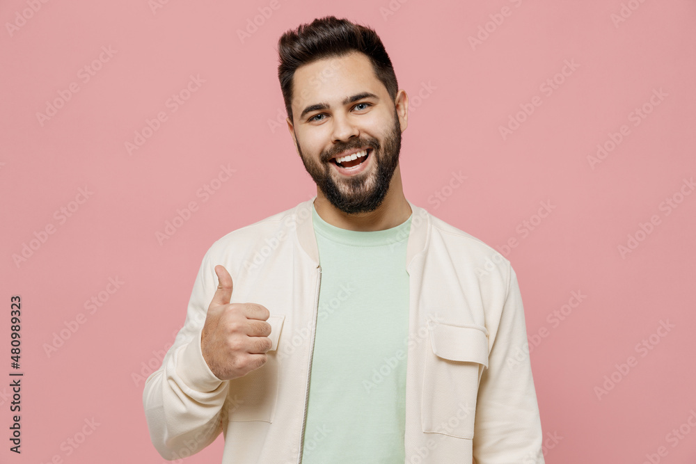 Young satisfied cheerful smiling happy caucasian man 20s in trendy jacket shirt showing thumb up like gesture isolated on plain pastel light pink background studio portrait. People lifestyle concept. Young satisfied cheerful smiling happy caucasian man 20s in trendy jacket shirt showing thumb up like gesture isolated on plain pastel light pink background studio portrait. People lifestyle concept.