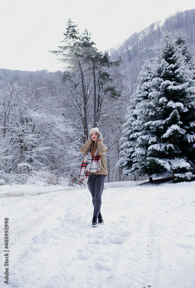 The model poses in winter clothes on the road. snowy winter