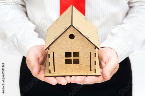 Businessman holding a house model in hands