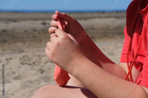 The girl has red slime in her hands. The girl is always enthusiastic about playing with slime, even on the beach playing with slime calms her down.