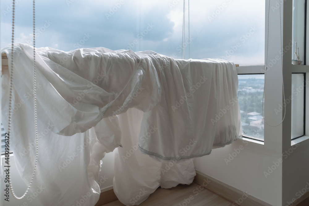 White Bed sheets and duvet clothes hanging on the balcony to dry in apartment. White Bed sheets and duvet clothes hanging on the balcony to dry in apartment.