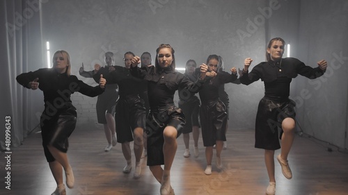 A group of beautiful girls dancing indoors in black suits. Dances
