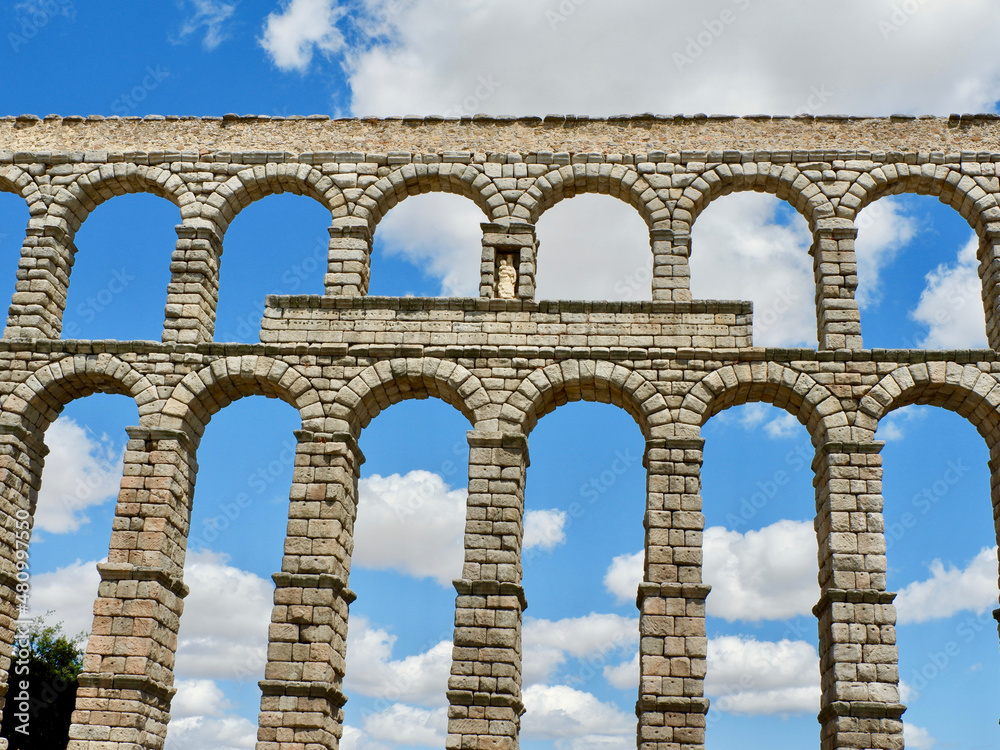 Front view of roman aqueduct in Segovia, Spain. Stone columns of medieval water transporting construction Front view of roman aqueduct in Segovia, Spain. Stone columns of medieval water transporting construction