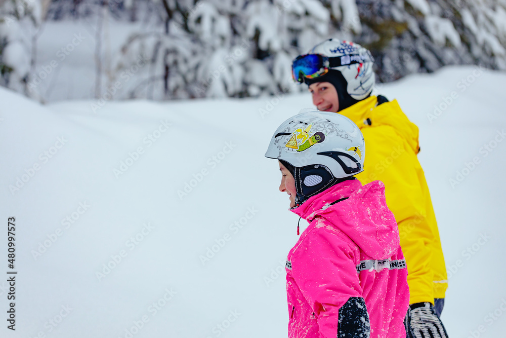 Happy mom and daughter spend time together on winter vacation. Young beautiful woman of Caucasian ethnicity and her daughter in bright winter sportswear. Active winter outdoor sports. Life style