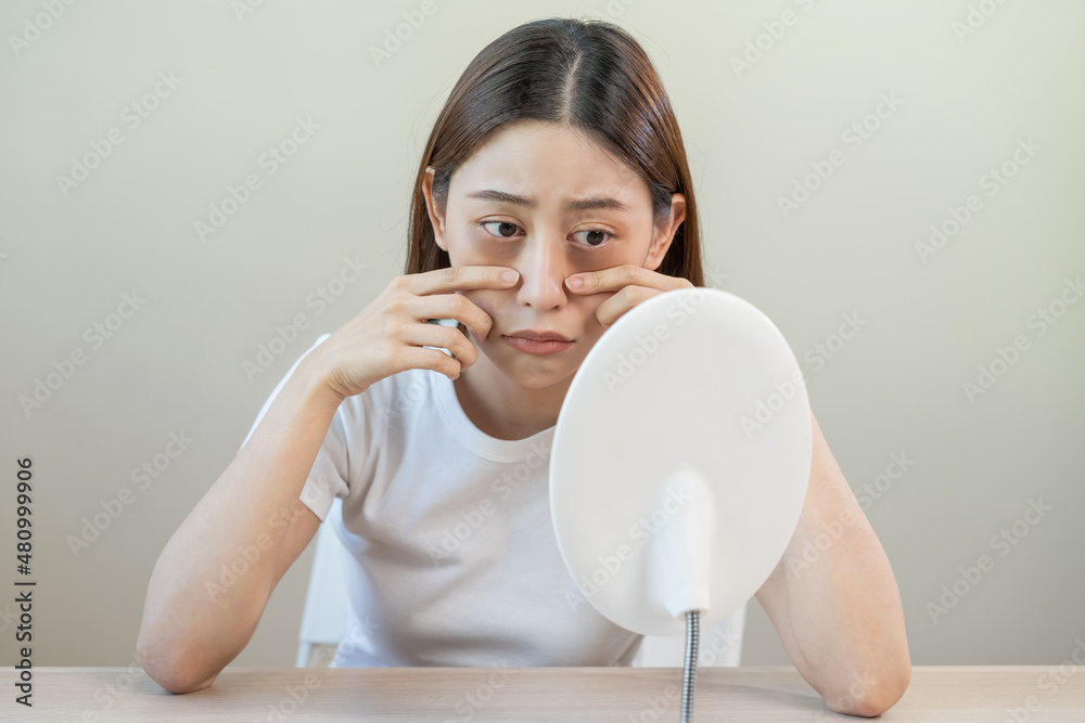 Bored, insomnia asian young woman, girl looking at mirror, without makeup, touch under eyes with problem of dark circles, puffiness, swollen or wrinkles on face. Sleepless, sleepy people, copy space Bored, insomnia asian young woman, girl looking at mirror, without makeup, touch under eyes with problem of dark circles, puffiness, swollen or wrinkles on face. Sleepless, sleepy people, copy space
