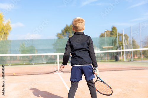 Little boy playing tennis. Tennis training for a child. Tennis lesson forhend beckend. photo