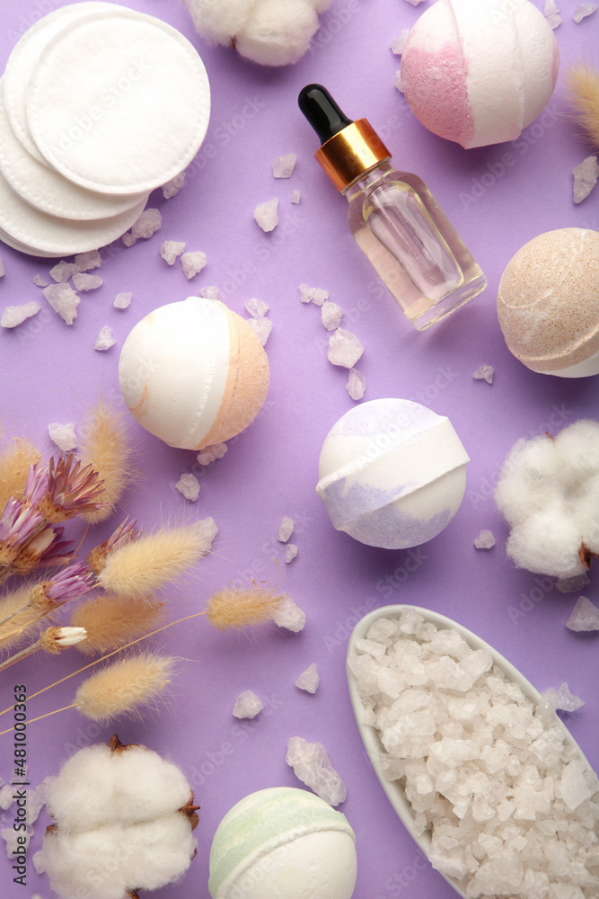 Composition with bath bombs, sea salt, dry flowers on purple background. Vertical photo