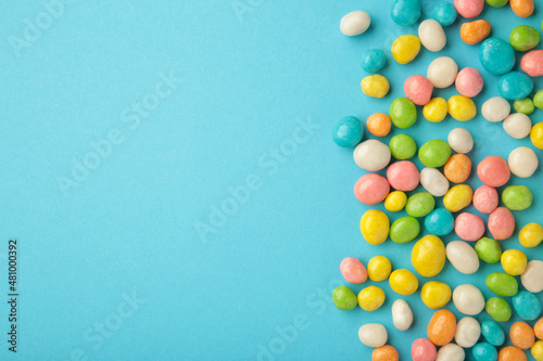 Colorful chocolate candy pills withs space on blue background.