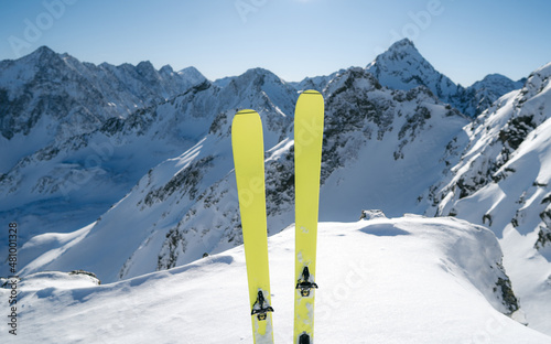 Yellow ski in winter season, mountains and ski touring equipments on the top in sunny day. Alps range tourism. Winter vacations. Snowy mountain background