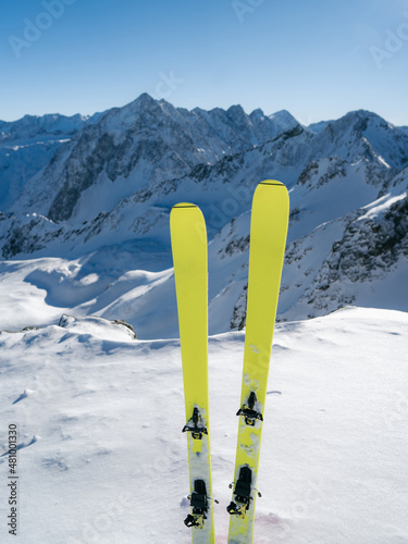 Yellow ski in winter season, mountains and ski touring equipments on the top in sunny day. Alps range tourism. Winter vacations. Snowy mountain background photo