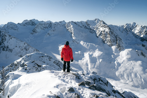 Ski mountaineer standing on top of mountain watching sun and blue sky on beautiful winter day with fresh snow, popular adrenaline activity,