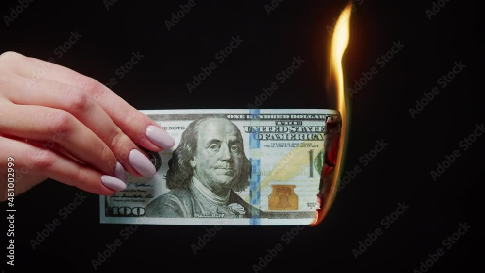 Woman holding burning American hundred dollar banknote on black background. Flame of fire from cash. Financial crisis and depressed economy. Paper money loss concept. 