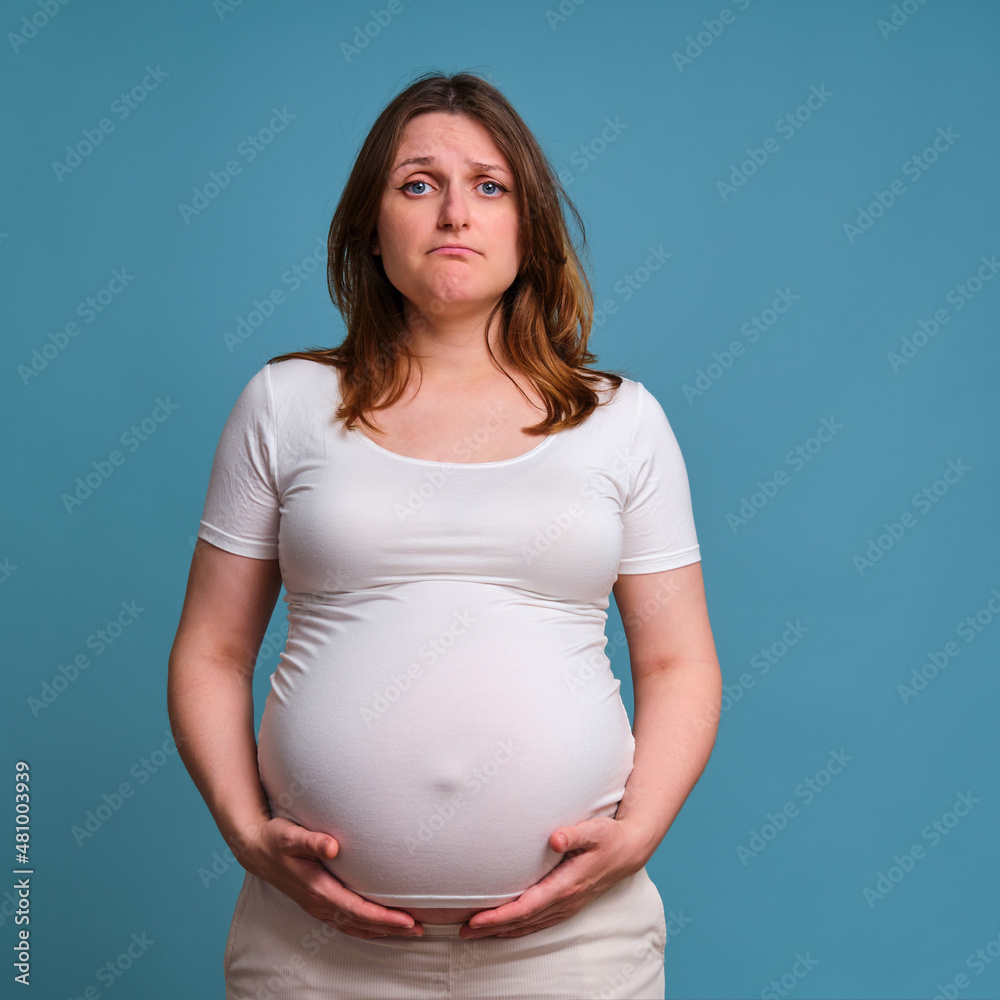 Sadness and negativity on face of pregnant woman, studio shot on blue background Sadness and negativity on face of pregnant woman, studio shot on blue background