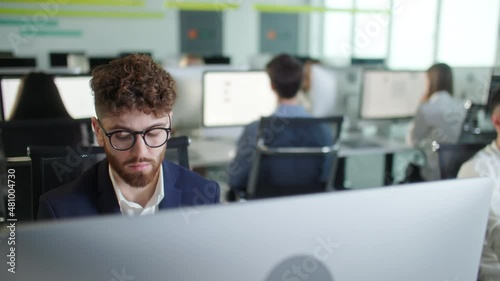 Professional Creative Businessman Working on Decktop Computer in Open Space Office . Male Professional Typing on PC Keyboard at Office Workplace. Portrait of Positive Business Man Looking at Computer photo