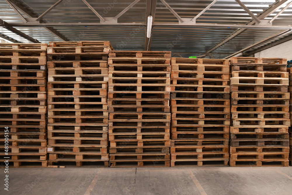Many empty wooden pallets stacked in warehouse Many empty wooden pallets stacked in warehouse