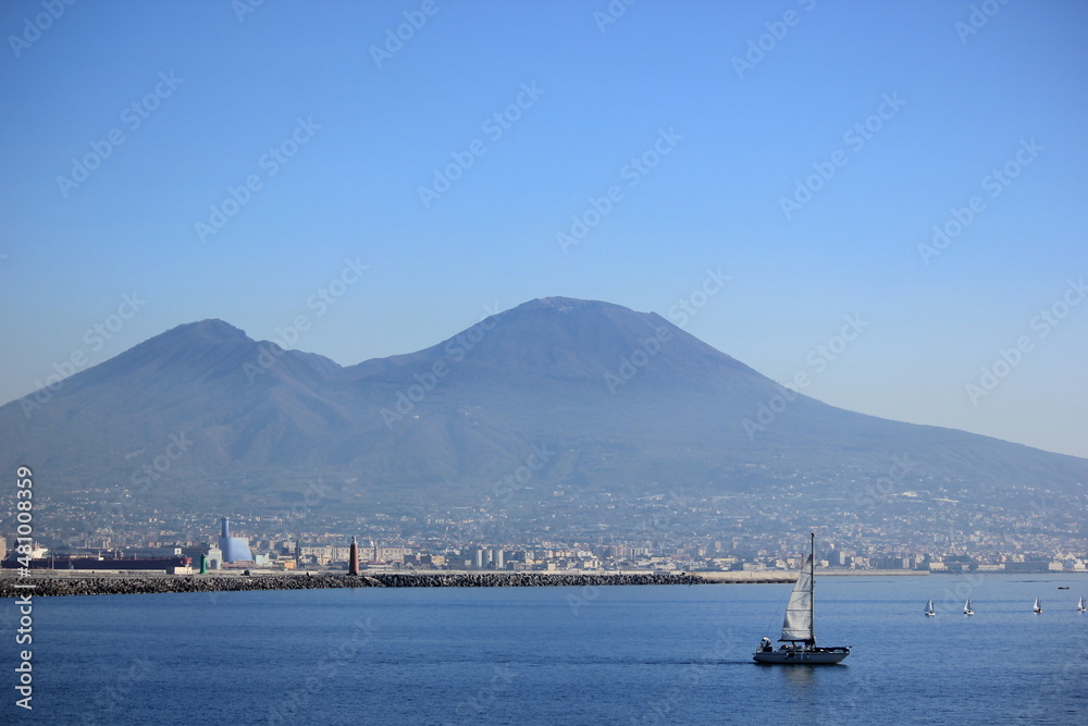 Naples Napoli Vesuvio background with sea view and sail boat in the foreground, promenade point of view