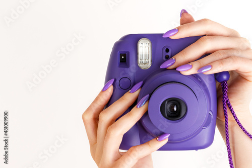 Beautiful female hands with a purple manicure hold a violet camera, beauty concept, nail`s design photo