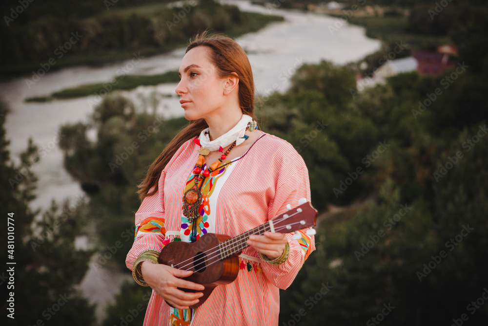 portrait young woman in ethnic dress lies with ukulele in hands portrait young woman in ethnic dress lies with ukulele in hands