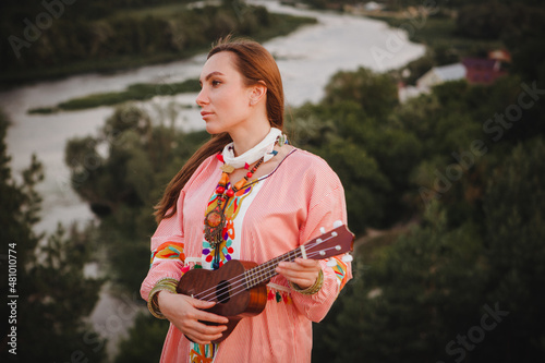 portrait young woman in ethnic dress lies with ukulele in hands
