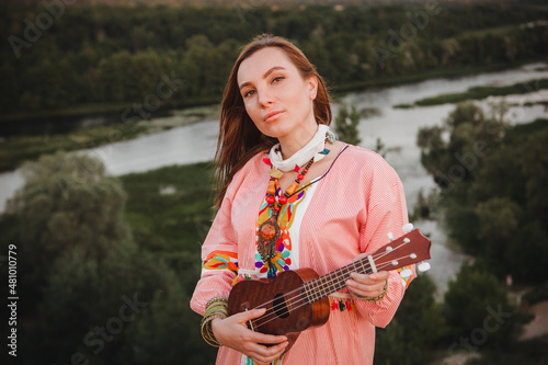 portrait young woman in ethnic dress lies with ukulele in hands
