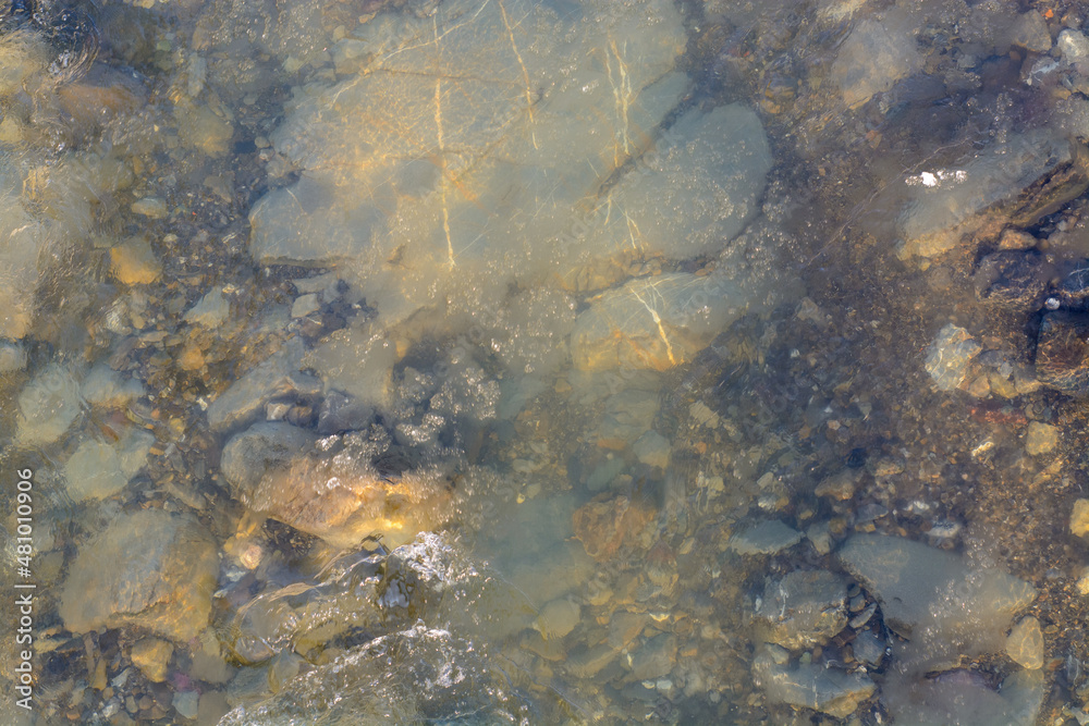 water flowing over rocks and ice in mountain river