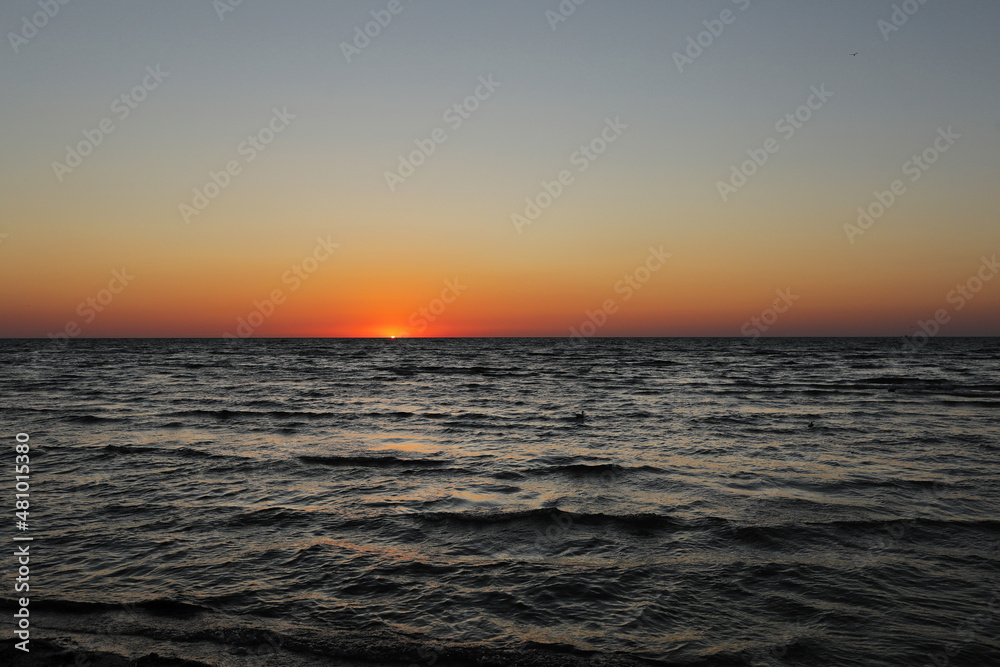 golden sunset or sunrise at the deep dark ocean. aerial view of sundown and up to the sea. yellow and orange colorful sky. romantic beautiful sky in the spring season.