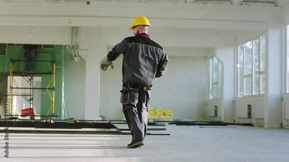 Charismatic and good dancing engineer man at construction site at the end of the day he wearing protective helmet and uniform. 4k
