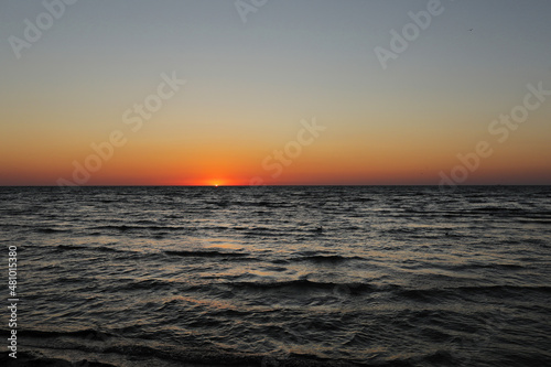 golden sunset or sunrise at the deep dark ocean. aerial view of sundown and up to the sea. yellow and orange colorful sky. romantic beautiful sky in the spring season.