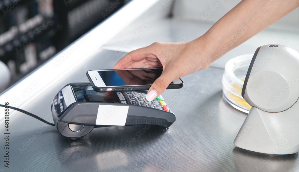 Fototapeta premium Customer paying for purchases contactless with smartphone.