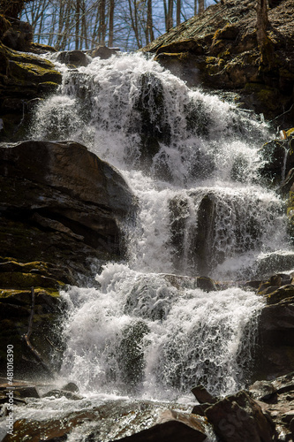 Cascading down a small mountain stream, the water runs over basalt boulders. A small waterfall runs through the moss. photo