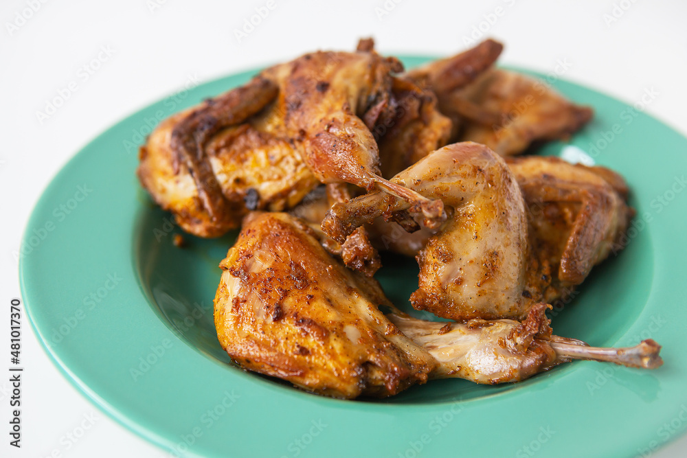 Delicious grilled fried quails lie on a green plate. Delicious and healthy meat. Delicious grilled fried quails lie on a green plate. Delicious and healthy meat.