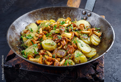 Traditionelle frische Pfifferlinge mit Bratkartoffeln und Petersilie serviert als close-up in einer klassischen Bratpfanne