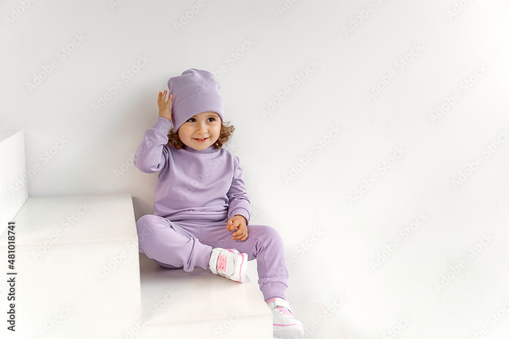 a little girl in a purple suit and hat on a light background is playing a little girl in a purple suit and hat on a light background is playing