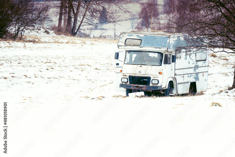 Abandoned old car in a snowy field near the forest. Vintage truck on the snow. Lonely mood background.