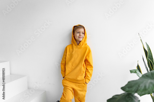 a teenager in a yellow tracksuit on a monochrome background in a hood