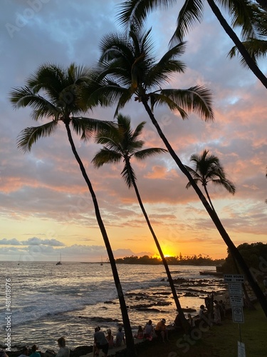 View of people enjoying sunset in Hawaii along ocean shore