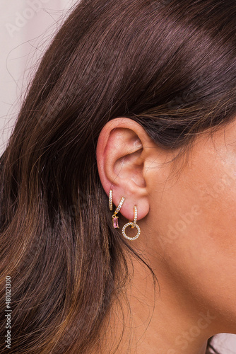 Woman ear with mulriple piercings wearing beautiful earrings with zirconia. Beautiful valentine's gift.