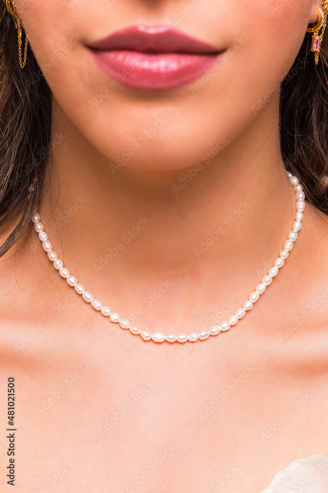 Beautiful young woman wearing a pearl necklace and golden earings.  Beautiful valentine's gift.