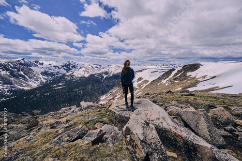 Young Woman standing on exposed rock in a snowfield in Rocky Mountains photo