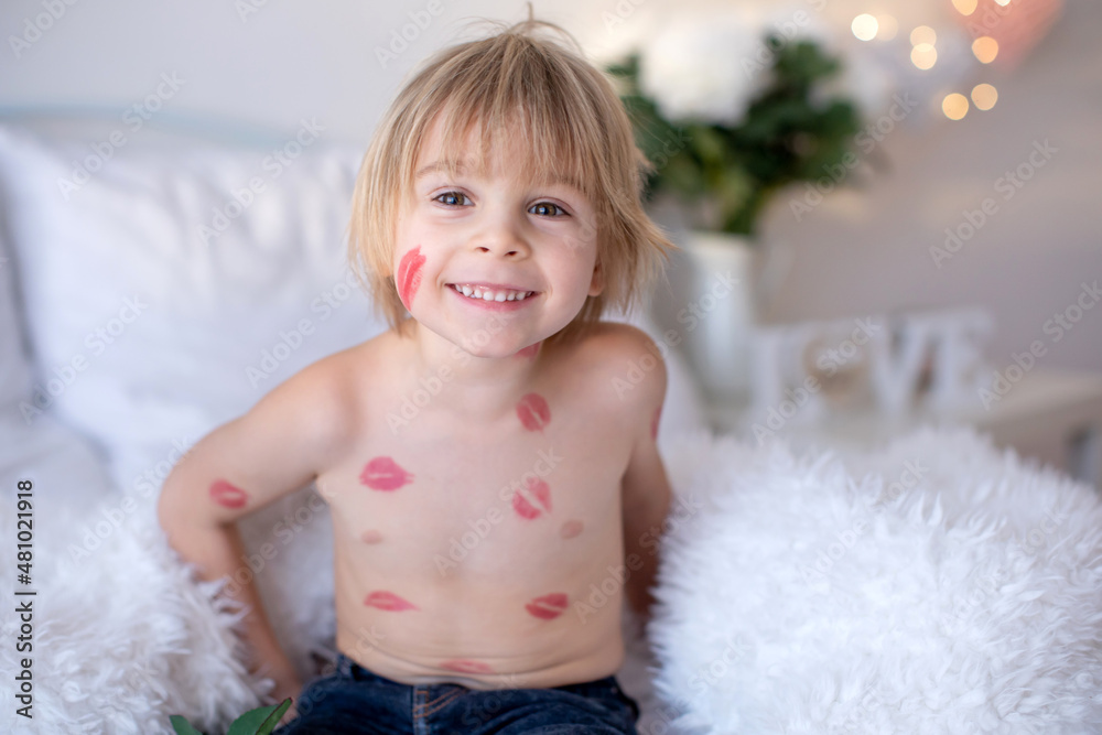 Beautiful blond toddler child, boy with lipstick kisses on his body, holding red rose for Valentine Beautiful blond toddler child, boy with lipstick kisses on his body, holding red rose for Valentine