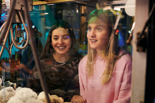 Two girls play in a claw machine to get soft toys photo