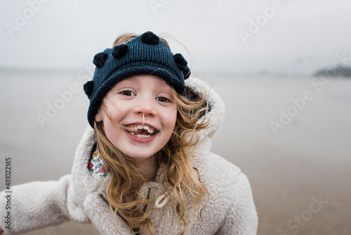 playful portrait of girl playing at the beach on a windy day photo