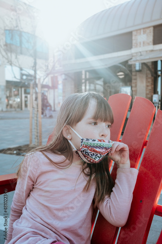 Young girl looking away and pulling down mask outside