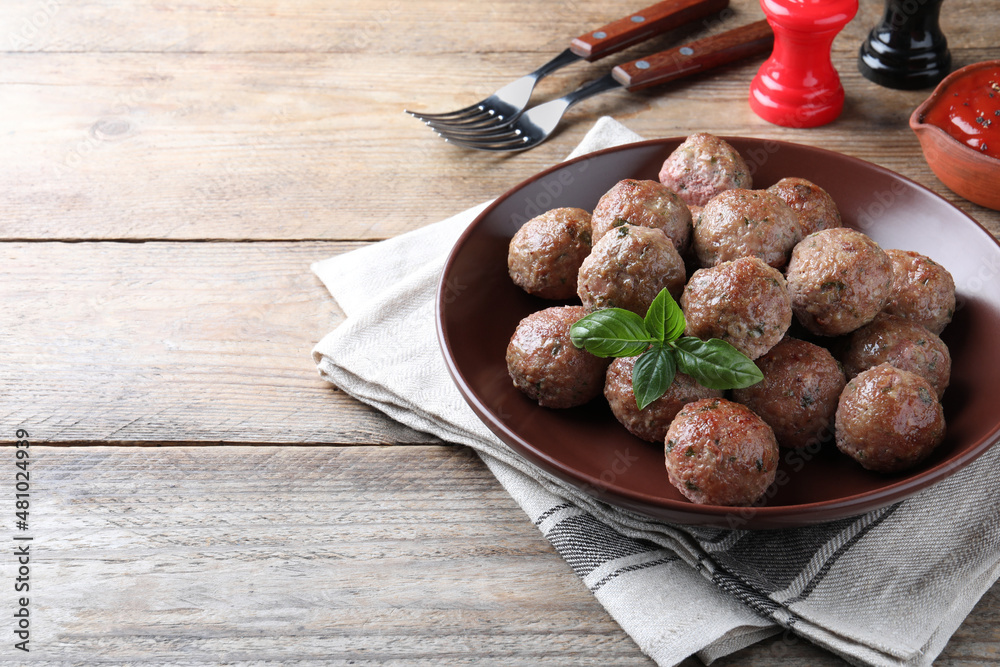 Tasty cooked meatballs with basil served on wooden table. Space for text Tasty cooked meatballs with basil served on wooden table. Space for text